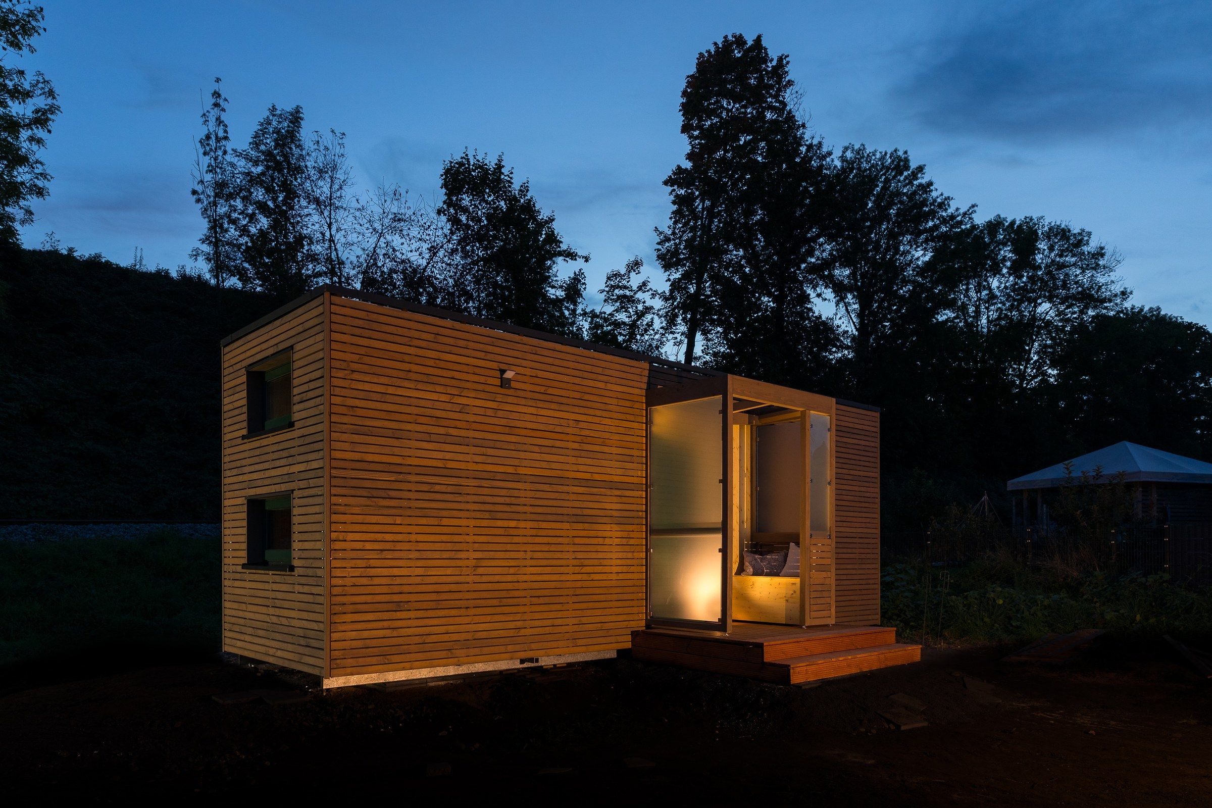 Tiny House am Abend mit beleuchteter Terrasse